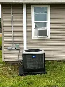 Outdoor residential HVAC condenser installed below a window