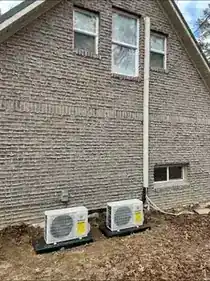 Two mini split outdoor units installed beside a home
