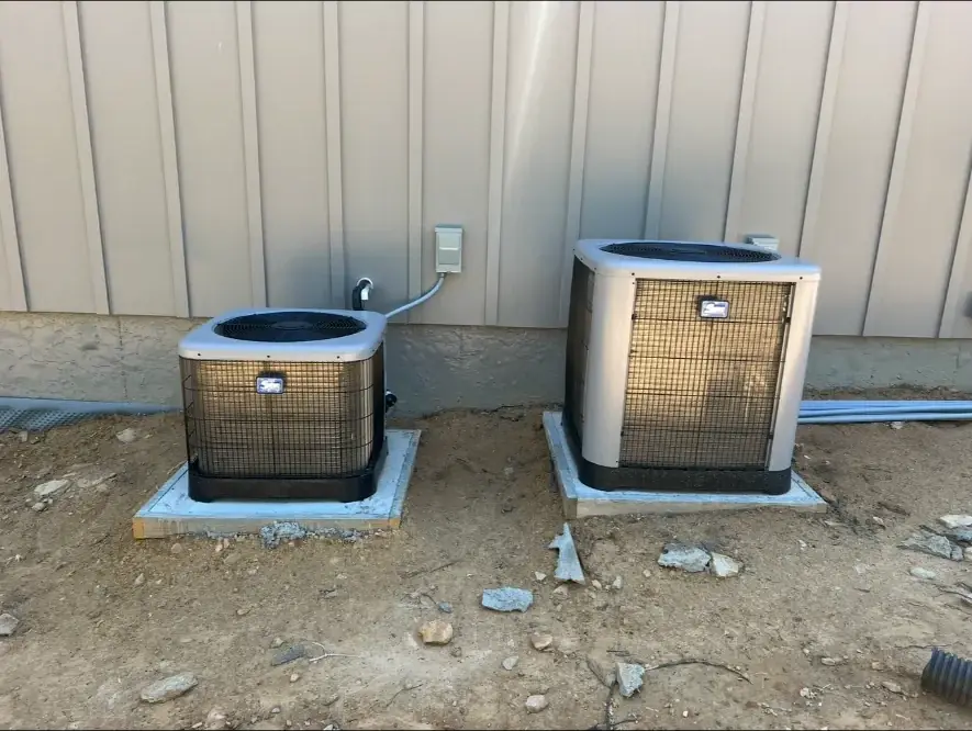 Two outdoor HVAC condensers installed on concrete pads