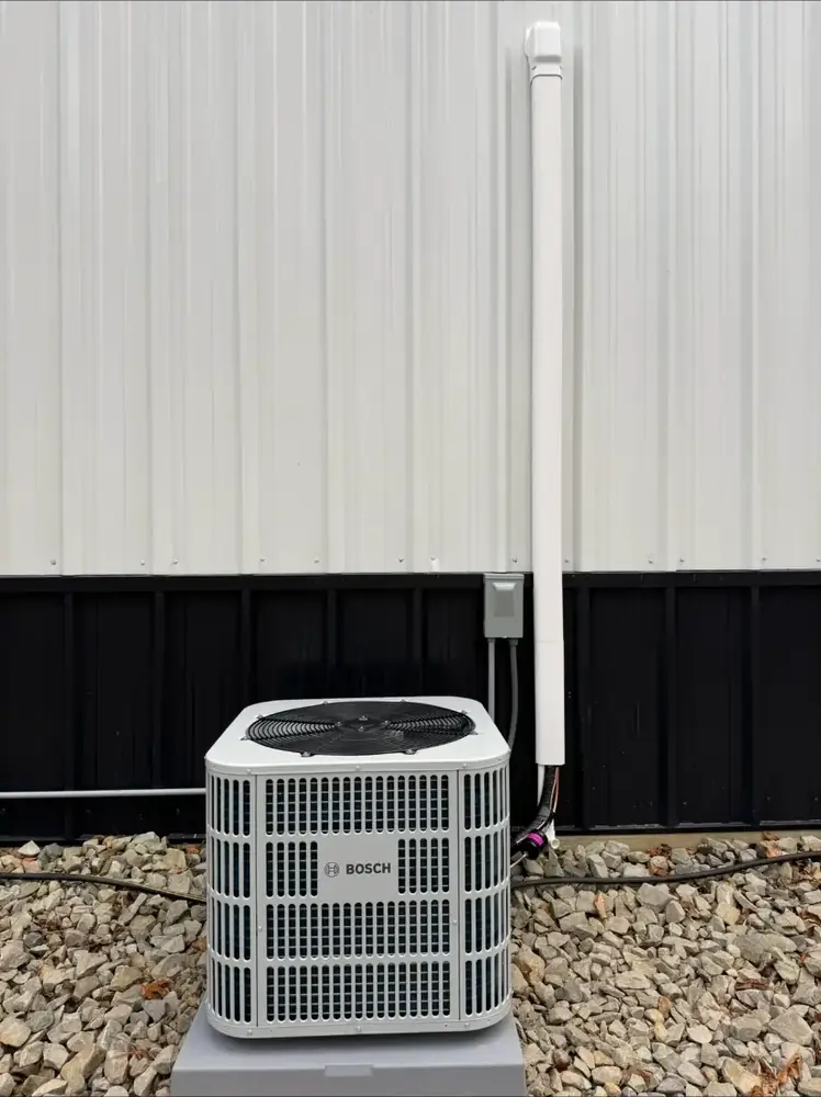 Bosch outdoor HVAC condenser installed on a pad beside a metal building
